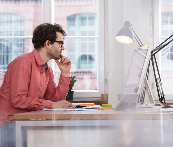 Person looking thoughtfully at computer while seated at desk