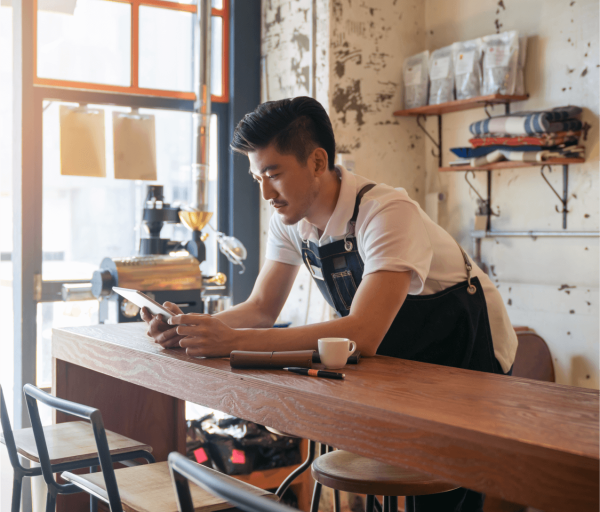 Worker taking a break and looking at tablet over a bar countertop